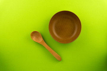 Wooden spoon, and bowl isolated on Green background.