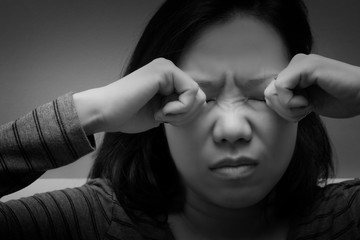 Asian woman rubbing her eyes by two hands. Concept of  eye's problem, dust allergy, dry eye, watery, itching or contact lenses problem. black and white tone