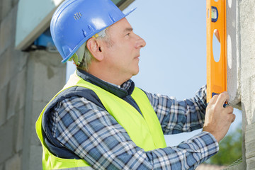 professional worker in helmet is measuring wall with level