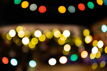 Shiny festive evening street decorated with a garland, light chains decorations night scene. Multicolored magical lights on a dark background. defocused bokeh effect abstract glitter