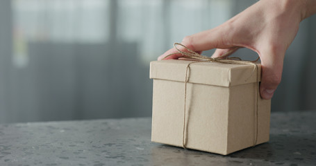 man hand bring brown paper gift box on terrazzo countertop