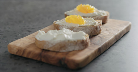 sweet bruschetta with orange marmalade and ricotta on olive board