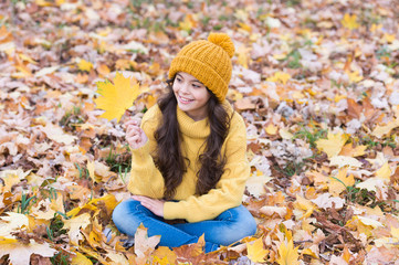 Playful mood. Warm woolen accessory. Girl long hair happy face fall nature background. Keep you warmest this autumn. Child in yellow hat outdoors. Hat keep warm. Kid wear warm soft knitted hat