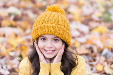 Lovely season. Autumn skin care routine. Kid wear warm knitted hat. Warm woolen accessory. Girl long hair happy face autumn nature background. Keep warmest this autumn. Child in yellow hat outdoors