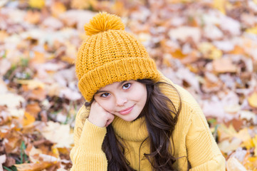 Autumn skin care routine. Kid wear warm knitted hat. Warm woolen accessory. Girl long hair happy face autumn nature background. Lovely season. Keep warmest this autumn. Child in yellow hat outdoors