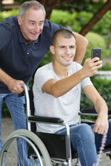 dad and son sitting in his wheelchair taking selfie