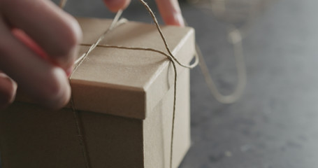 man hand ties bow on brown paper box