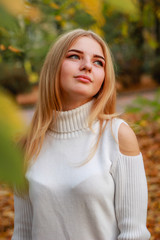 Autumn girl portraits. Model in white sweater Yellow leaves. Atmospheric photos.