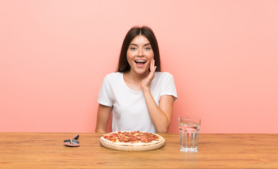 Obraz na płótnie Canvas Young woman with a pizza with surprise and shocked facial expression
