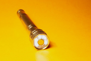 Metal led flashlight on a yellow background