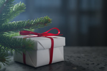 White gift box red ribbon under spruce twig on terrazzo countertop with copy space