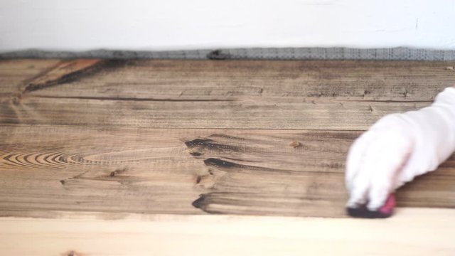 repair and decoration. the master applies an environmentally friendly coating on the wooden floor - natural oil wax dark