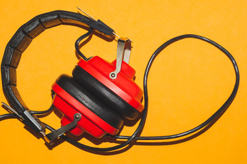 Vintage red headphones on yellow background. classic earphones