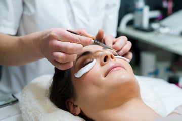 close up of beautician tweezing patients eyebrows