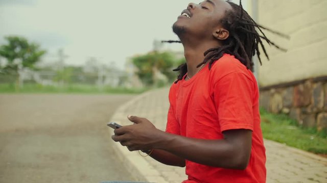  skateboarder sitting on the ramp of the road using his phone and moving his dreads slow motion