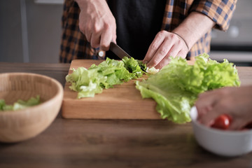 Man cutting green lettuce for salad