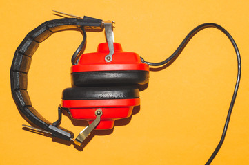 Vintage red headphones on yellow background. classic earphones