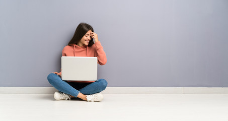 Young student girl with a laptop on the floor laughing