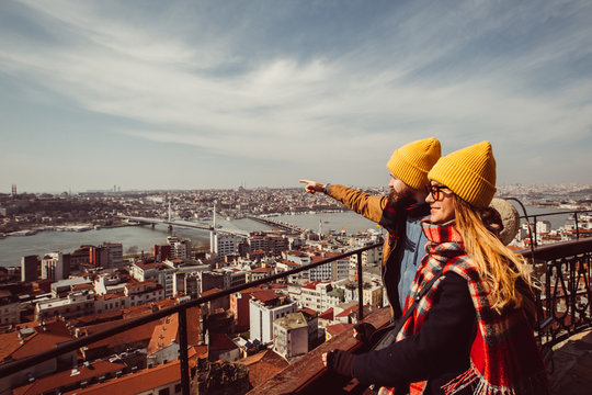 young couple on the background of the panorama of Istanbul on sunny spring day. guy and girl in yellow hats are looking at Istanbul from the observation deck of the Galata Tower.