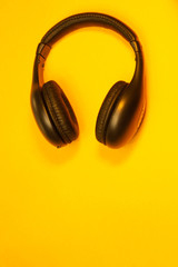 Black wireless headphones on a yellow background