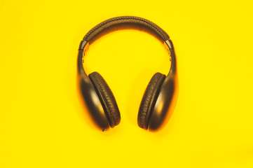 Black wireless headphones on a yellow background