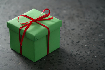 Green gift box with red ribbon on terrazo countertop with copy space