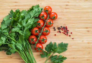 Fresh vegetables on the table, copy space. Food background. Flat lay. Cherry tomatoes, a bunch of parsley, black and red peppers on a wooden chopping board. Ingredients for pickling or salads