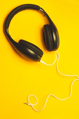 Headphones with white cable on a yellow background