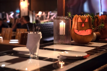 A pumpkin in the form of a smiling face is standing on the bar on the eve of the helloween holiday