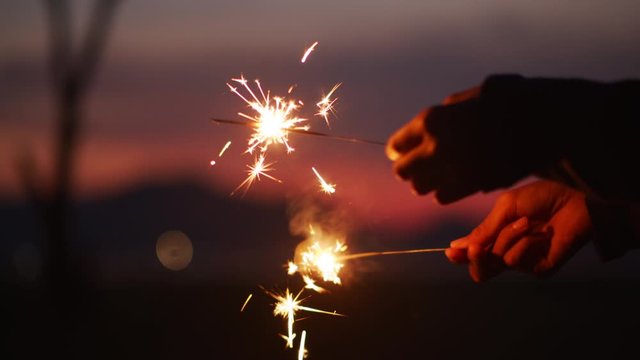 Hand of little girl holding a sparkler in the midst of Nature at night.
