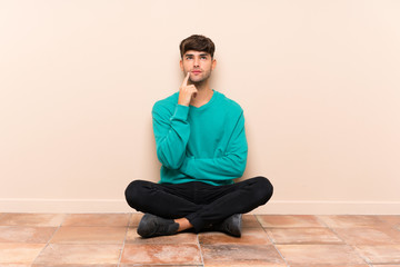 Young handsome man sitting on the floor thinking an idea