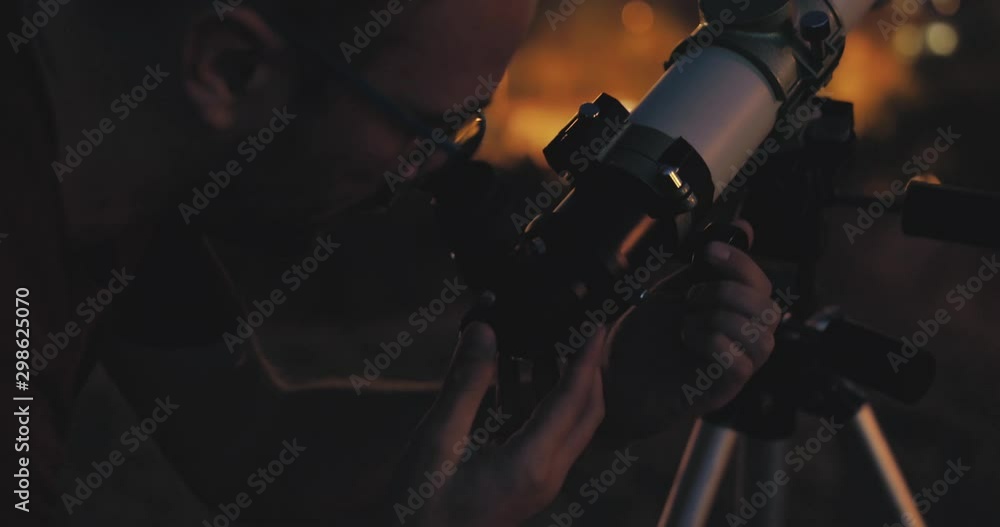 Canvas Prints astronomer with a telescope watching at the stars and moon with blurred city lights in the backgroun