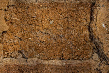 Wall of clay blocks with broken plaster.