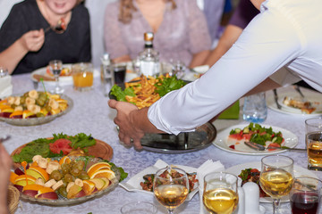 Obraz na płótnie Canvas A rich table with food, the hand of the waiter, dishes, restaurant.