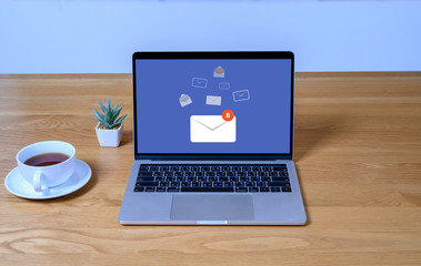 Fototapeta premium Laptop computer on wooden table with email communication connection message online and chat on social media with global letters concept. Laptop mockup with clipping path on screen.