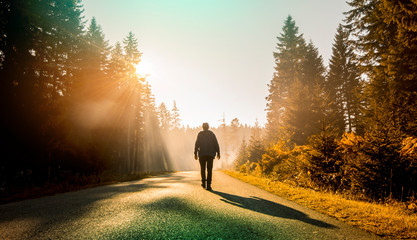 man walking on country road at sunset