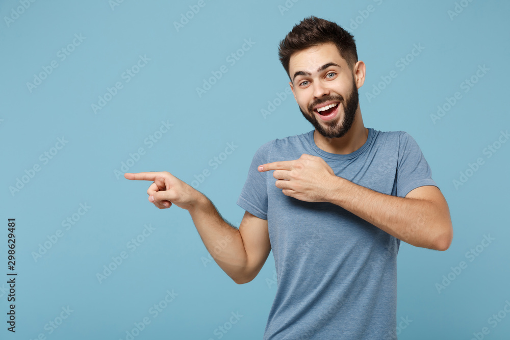 Wall mural young cheerful smiling funny man in casual clothes posing isolated on blue background, studio portra