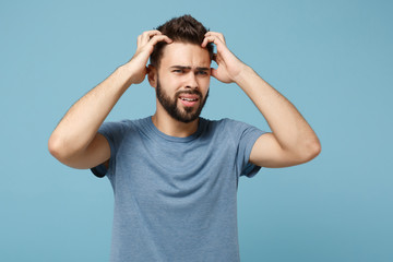 Young nervous preoccupied man in casual clothes posing isolated on blue background studio portrait. People sincere emotions lifestyle concept. Mock up copy space. Looking aside, putting hands on head.