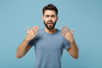 Young shocked concerned preoccupied man in casual clothes posing isolated on blue background, studio portrait. People sincere emotions lifestyle concept. Mock up copy space. Spreading hands.