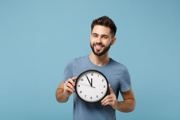 Young smiling attractive man in casual clothes posing isolated on blue wall background, studio...