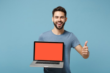 Young laughing man in casual clothes posing isolated on blue wall background in studio. People...