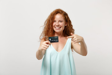 Young pretty redhead woman girl in casual light clothes posing isolated on white background, studio portrait. People lifestyle concept. Mock up copy space. Pointing index finger on credit bank card.