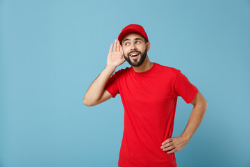 Delivery man in red uniform workwear isolated on blue wall background, studio portrait....