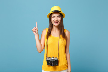 Traveler tourist woman in yellow summer casual clothes, hat with photo camera isolated on blue background. Female passenger traveling abroad to travel on weekends getaway. Air flight journey concept.