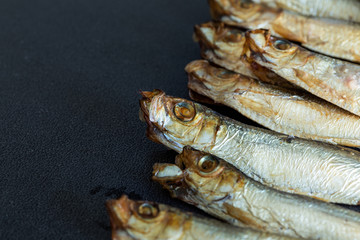 Smoked sprats on a dark background with empty space for your own text