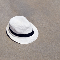 Fototapeta na wymiar Beach white hat lying on the sand. Seaside resort. Vacation at sea.