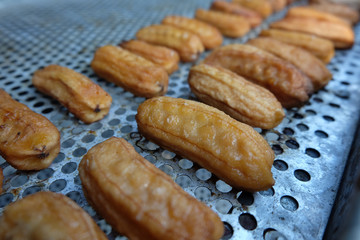 Dried bananas are drying on a metal wire rack.