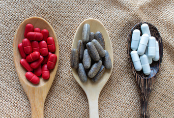 Medicine pill group in wooden spoon on a sack background,