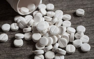 Fototapeta na wymiar White painkiller pills on wooden table close-up