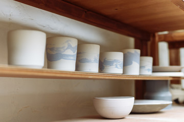 Fototapeta na wymiar Blank Potter on the shelf of the workshop. Ceramic tableware templates
